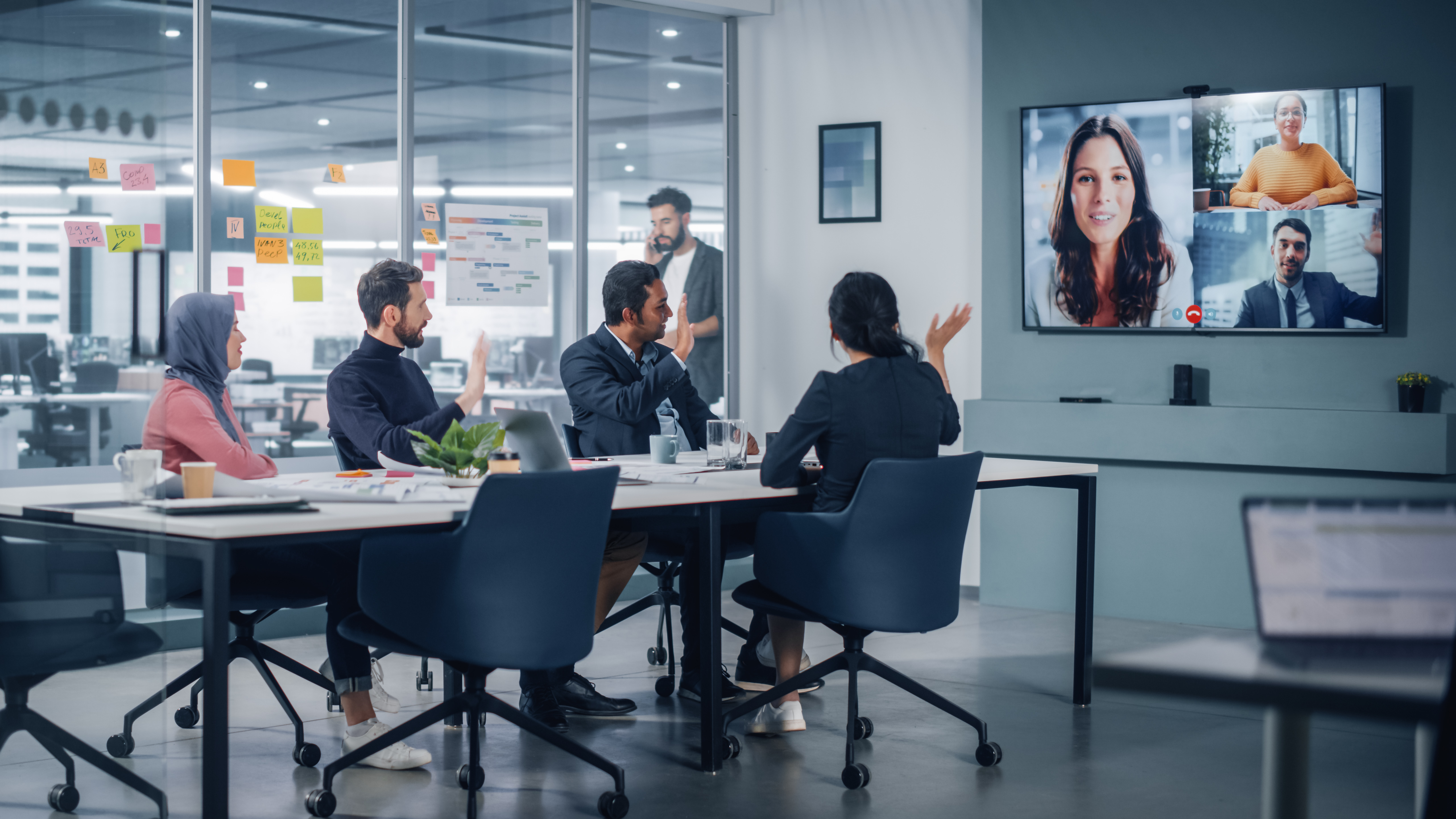 Team working at a table with remote colleagues on a screen
